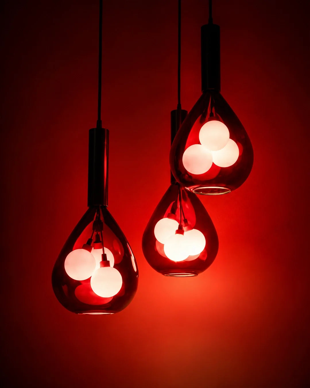 Grapa Pendant — group of red glass pendants against a red wall | دلاية جرابا، مجموعة دلايات زجاجية حمراء أمام حائط أحمر