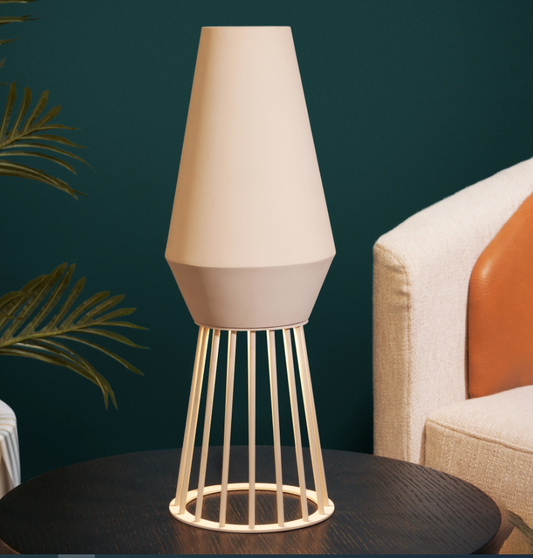 Beam Table Lamp — pale tapered shade and open gold base on a side table | أباجورة بيم، غطاء فاتح وقاعدة ذهبية مفتوحة على طاولة جانبية
