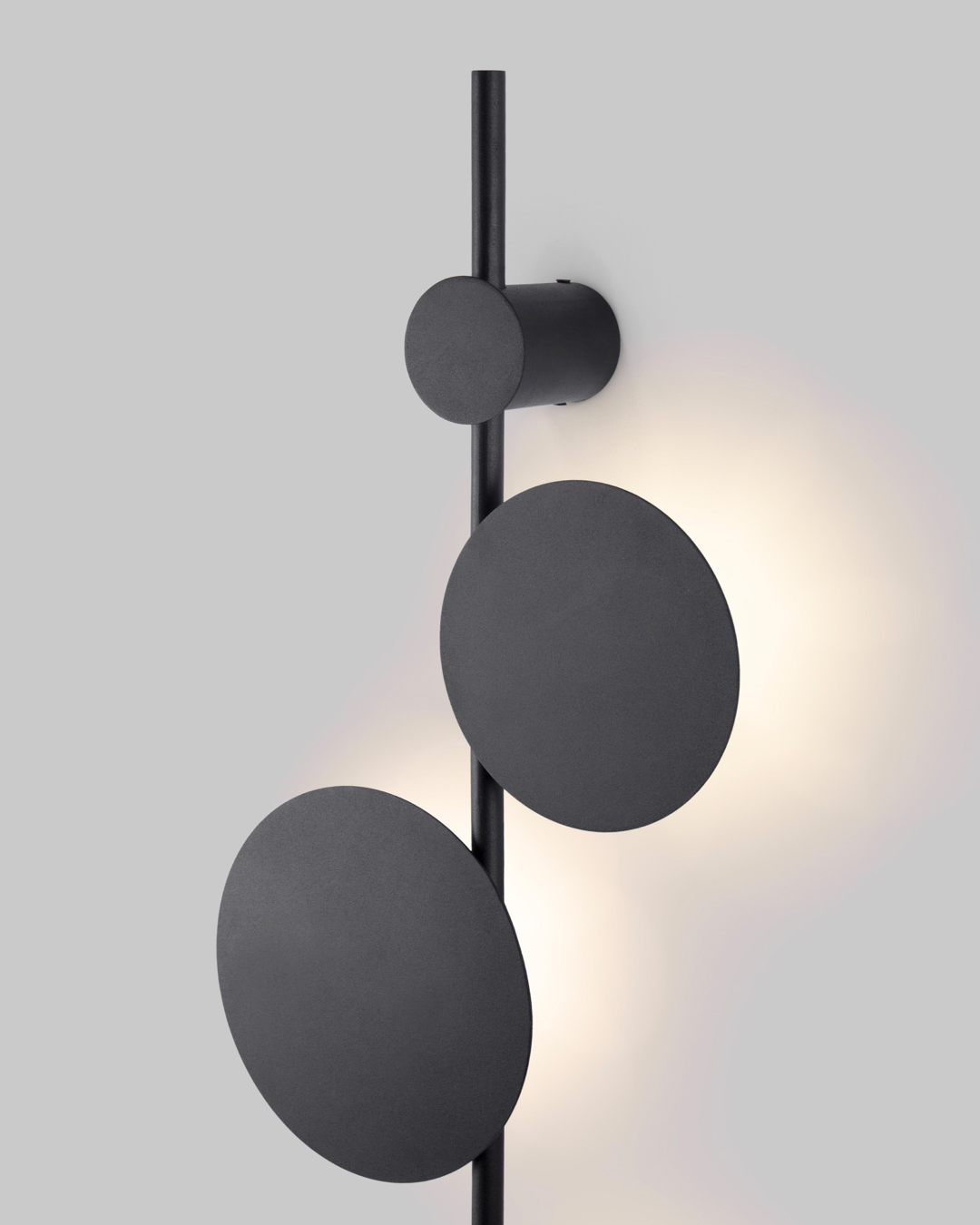 Vertical trio wall lamp with three circular elements creating soft ambient lighting / مصباح حائط عمودي بثلاث وحدات دائرية يوفّر إضاءة هادئة ولمسة فنية