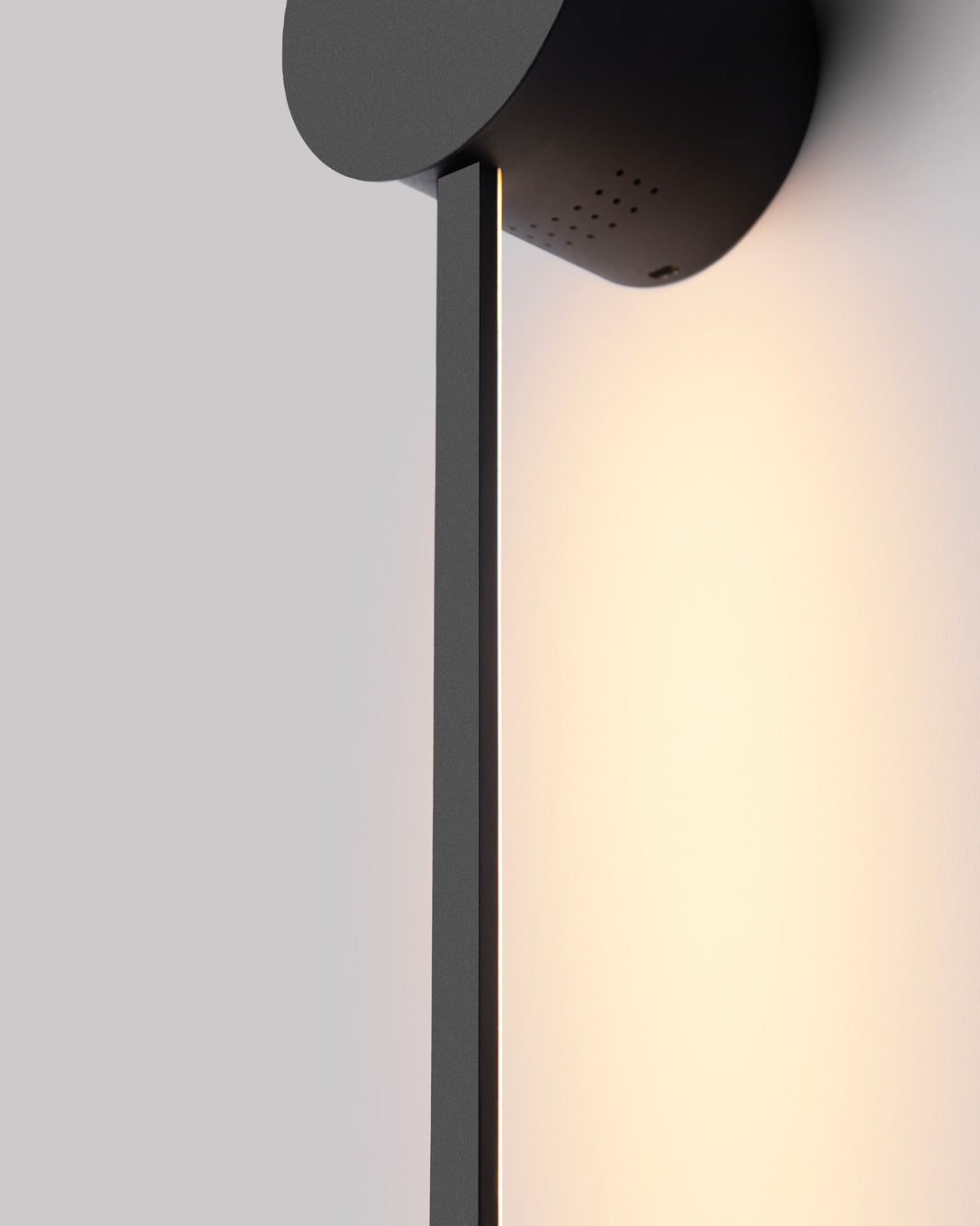 Black wall lamp with linear lines and circular element creating soft indirect light / مصباح حائط أسود بخطوط هندسية ودائرة يبعث إضاءة غير مباشرة ناعمة