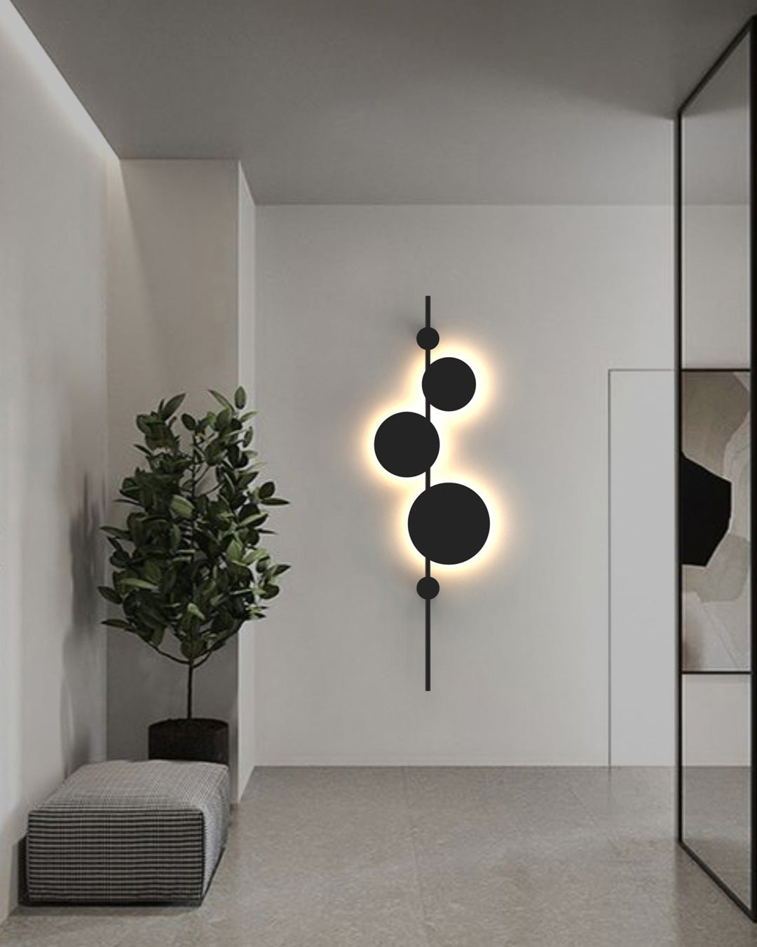 Vertical trio wall lamp with three circular elements creating soft ambient lighting / مصباح حائط عمودي بثلاث وحدات دائرية يوفّر إضاءة هادئة ولمسة فنية