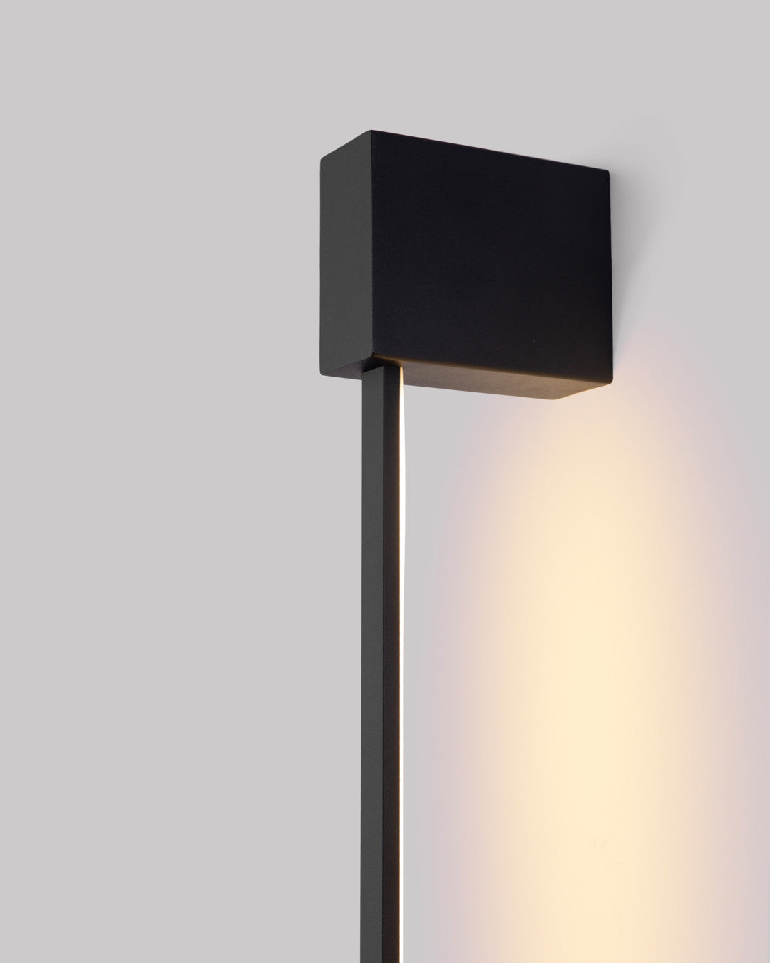 Black square wall lamp with linear design casting soft indirect light / مصباح حائط أسود مربع بخطوط هندسية يبعث إضاءة غير مباشرة ناعمة