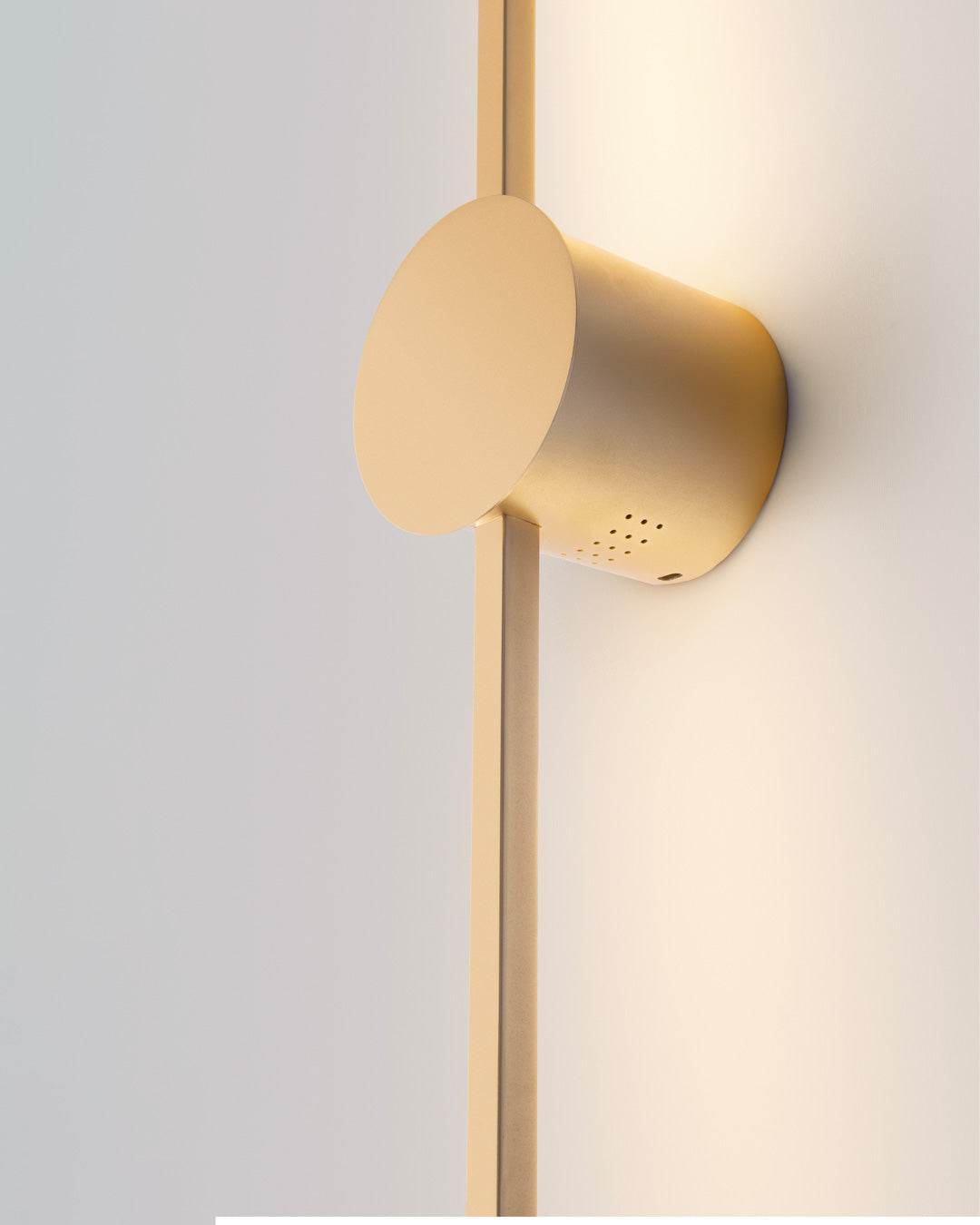 Gold wall lamp with double vertical lines and central circle casting soft indirect light / مصباح حائط ذهبي بخطين رأسيين ودائرة مركزية يبعث إضاءة غير مباشرة ناعمة