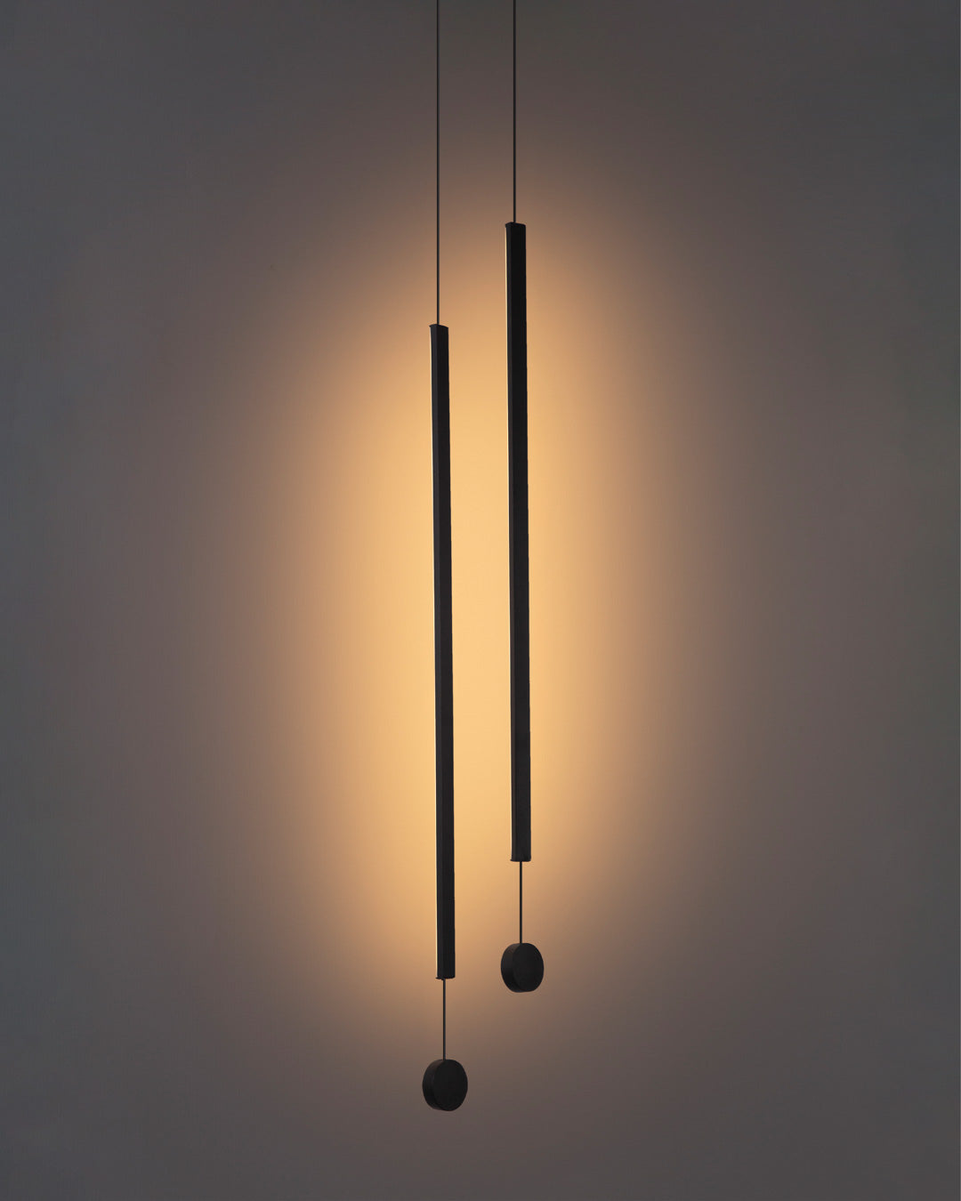 Two lines pendant light with slim vertical black rods creating warm ambient lighting / إضاءة معلقة بخطين بتصميم طولي نحيف باللون الأسود تضيف إضاءة دافئة وعصرية